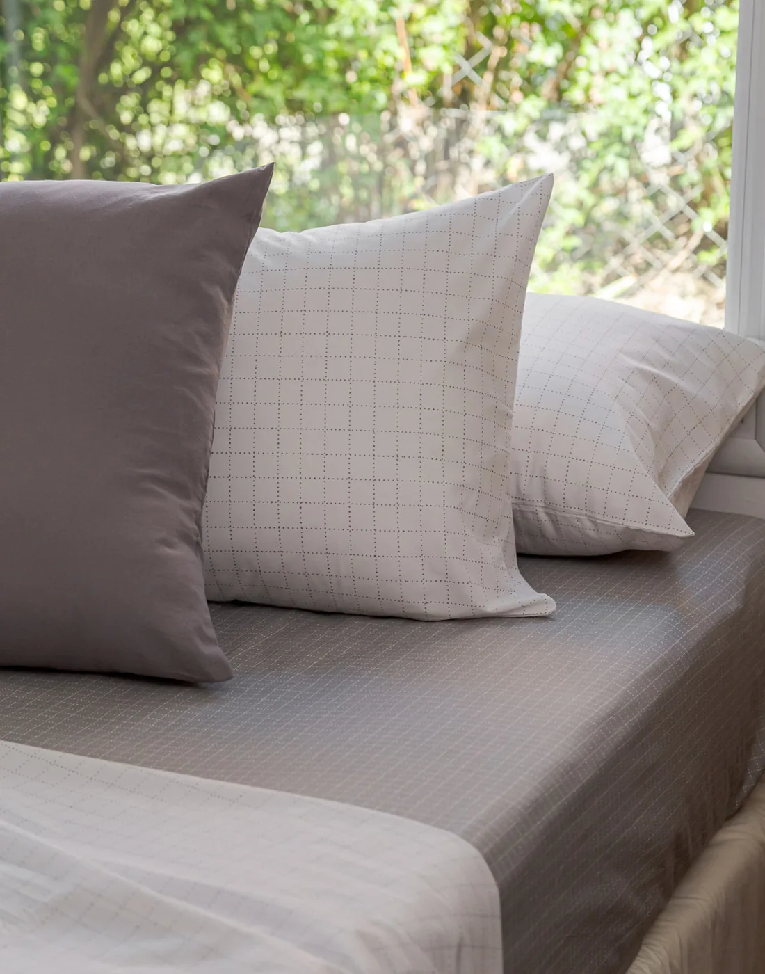 Almohadas y sábanas Brescia en gris y blanco, detalle de la ropa de cama