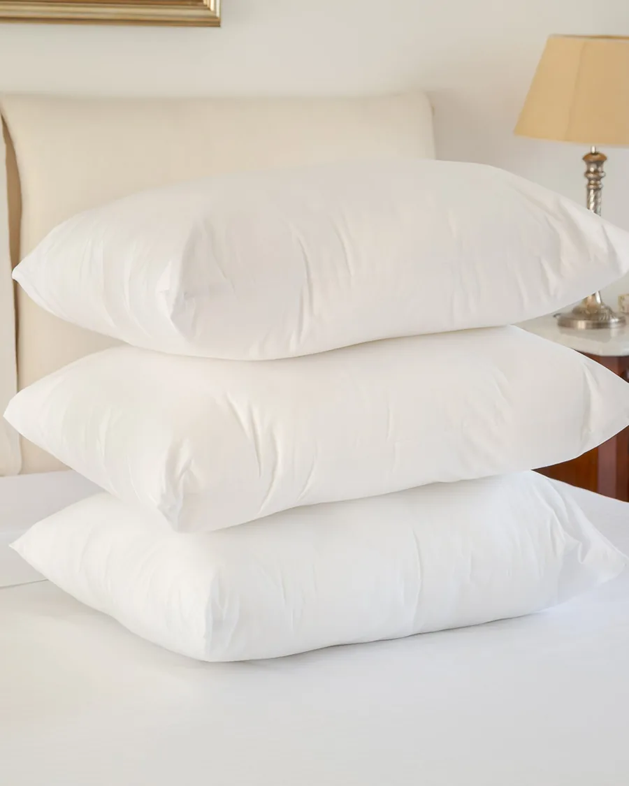 Tres almohadas blancas Brescia apiladas sobre la cama