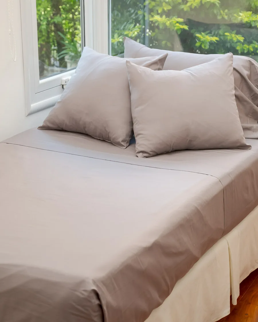 Juego de sábanas Brescia en gris tendido sobre la cama, con fundas y volado